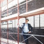 Architect wearing hard hat standing on scaffolding on constructi